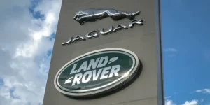Jaguar Land Rover dealership sign under a blue sky, representing the growing group litigation for Jaguar owners over alleged diesel particulate filter defects.