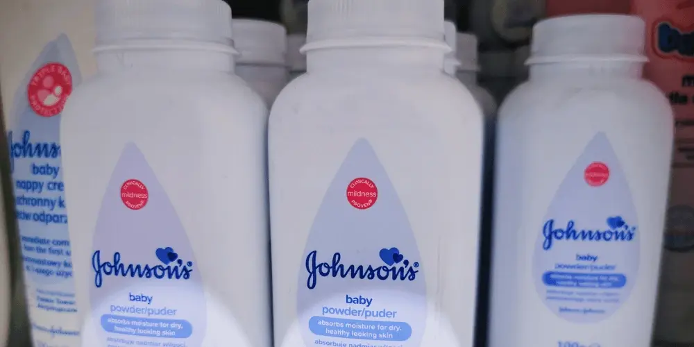 Several bottles of Johnson's baby powder on a store shelf, symbolising the Johnson and Johnson talc lawsuit over alleged asbestos contamination and cancer risks.