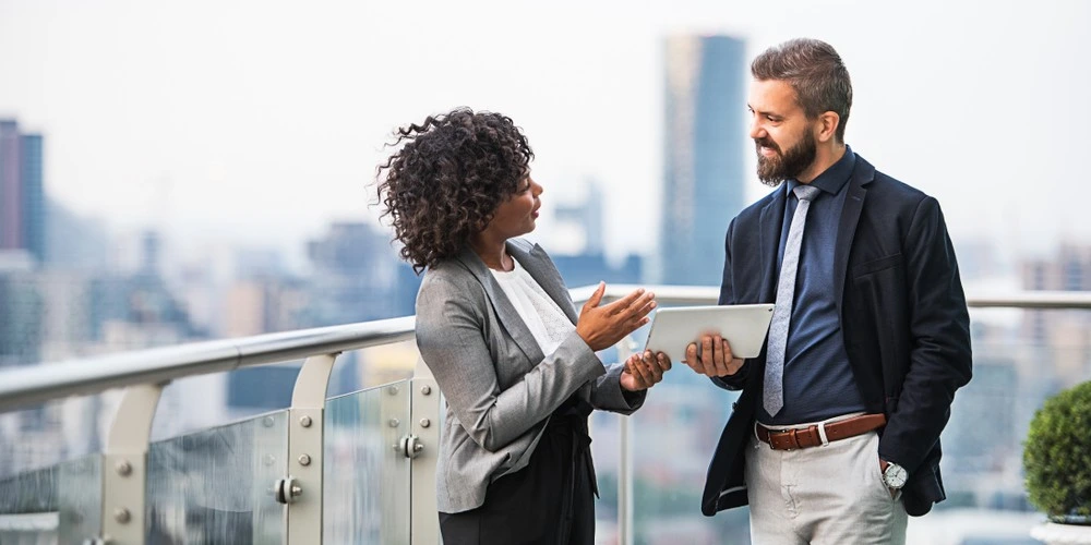 A portrait of two businesspeople with tablet standing against London view panorama.
