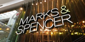 Marks Spencer Shop Sign on glass window with warm lighting behind.