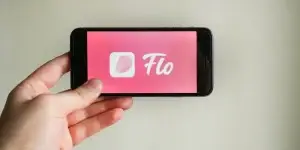 Young woman hand holding iphone with logo of Flo application. Flo - is tracking menstruation and menopause, and ovulation calendar.