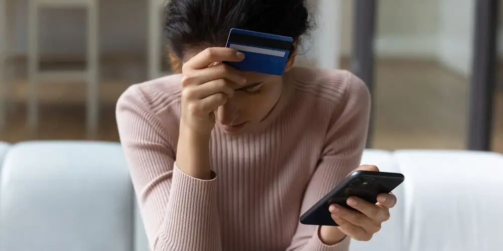 Frustrated young woman having lost savings due to app fraud.