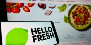 Cellphone with logo of HelloFresh on screen in front of business website.