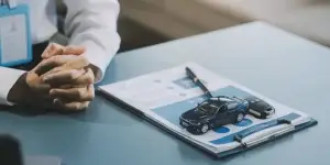 Close up hand of agent dealer giving, holding car key to customer renter, new owner after signed rental, purchase contract in document, vehicle finance agreement.