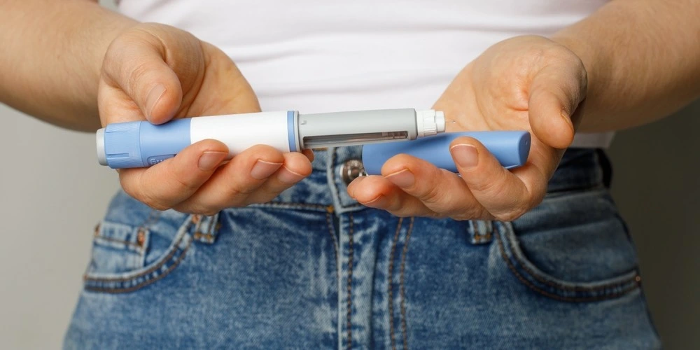 Semaglutide Injection pen closeup. Semaglutide or insulin drug against female belly.