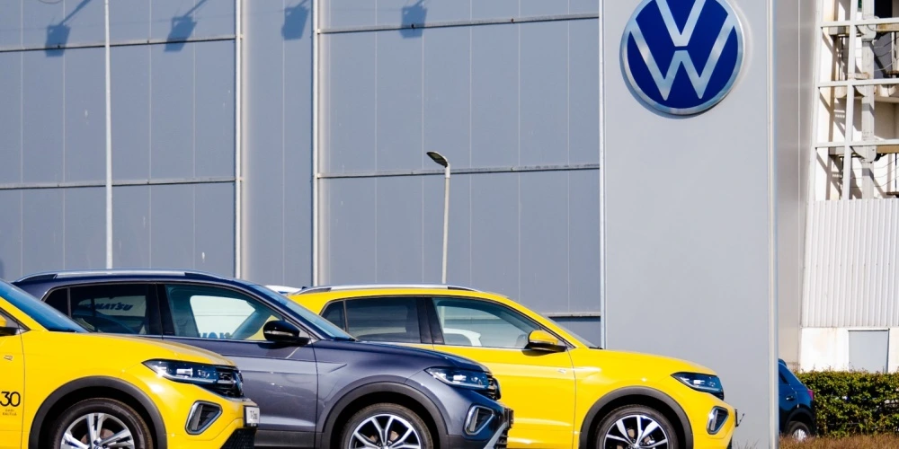 two yellow cars and a grey car parked in front of a Volkswagen shop