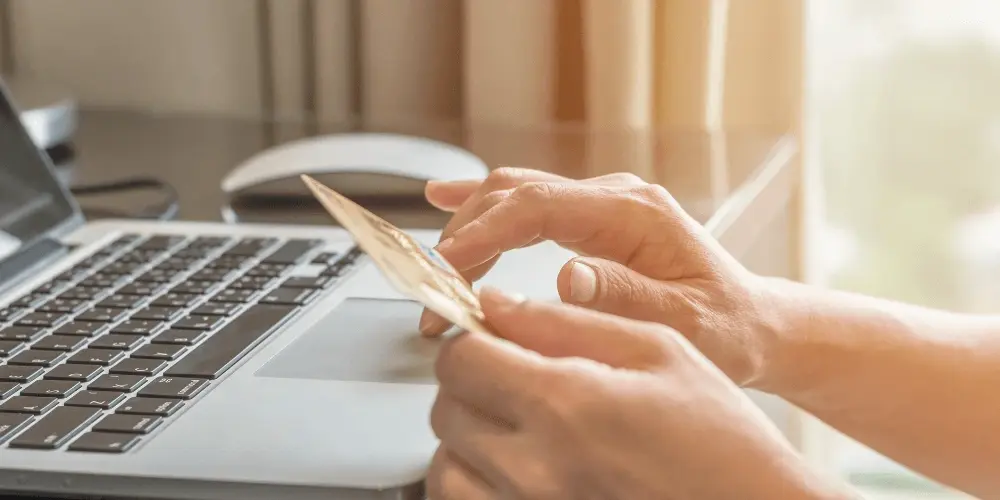 Hands holding a credit card in front of a laptop, symbolising the importance of understanding consumer rights when making purchases and online transactions.