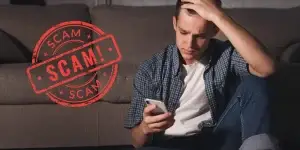 Man holding a phone looking distressed because of a scam app situation