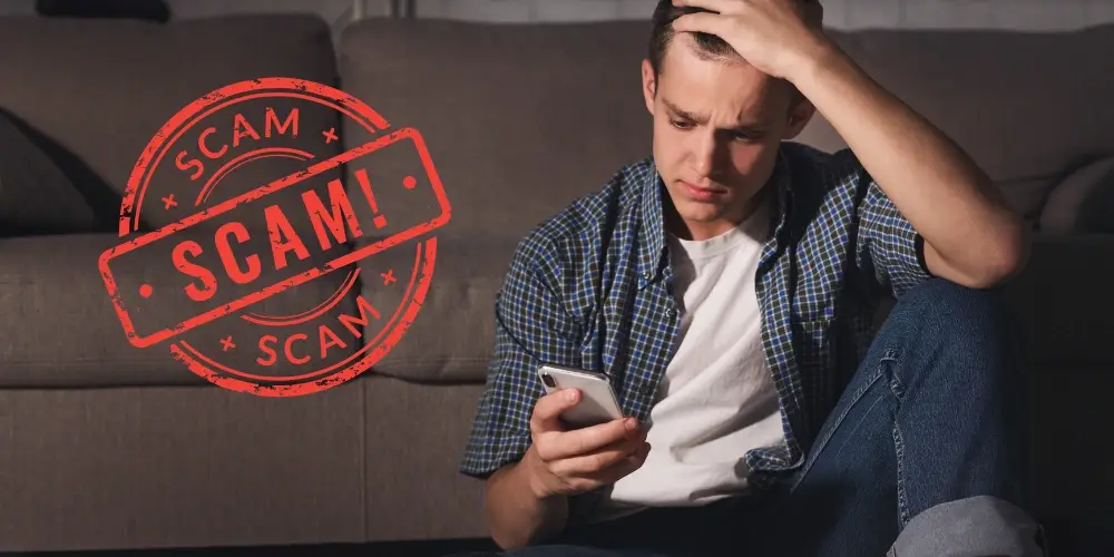 Man holding a phone looking distressed because of a scam app situation